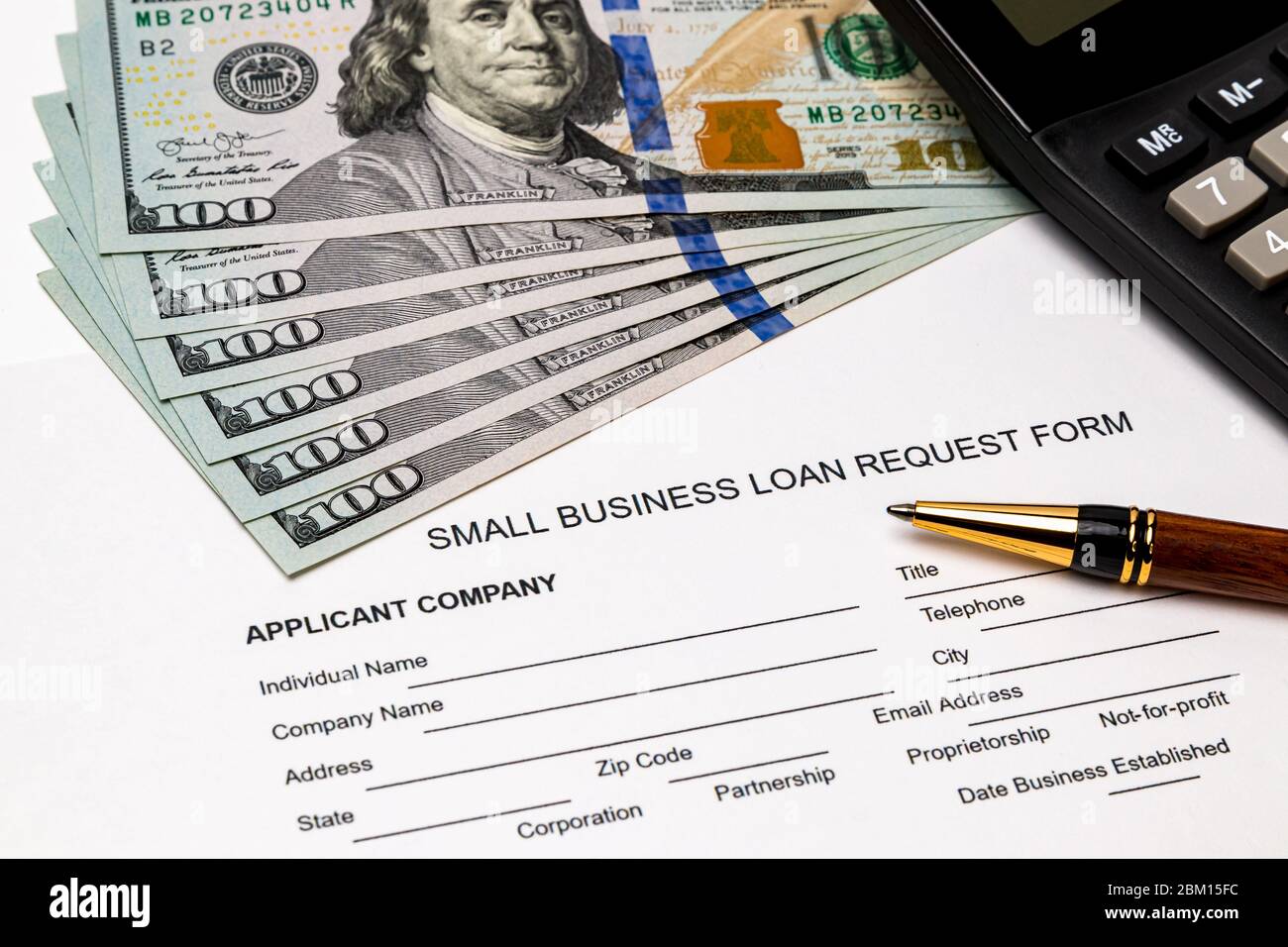 Small business loan form, 100 dollar bills. Concept of financial assistance, stimulus payment and recession during Covid-19 coronavirus pandemic Stock Photo