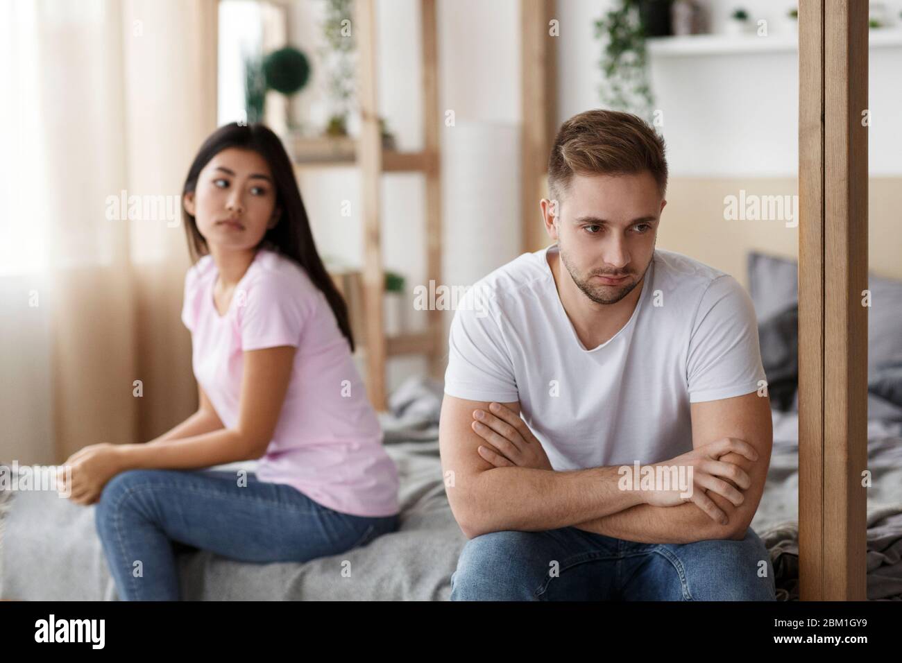 Couple After Quarrel Sitting On Bed At Home Stock Photo - Alamy