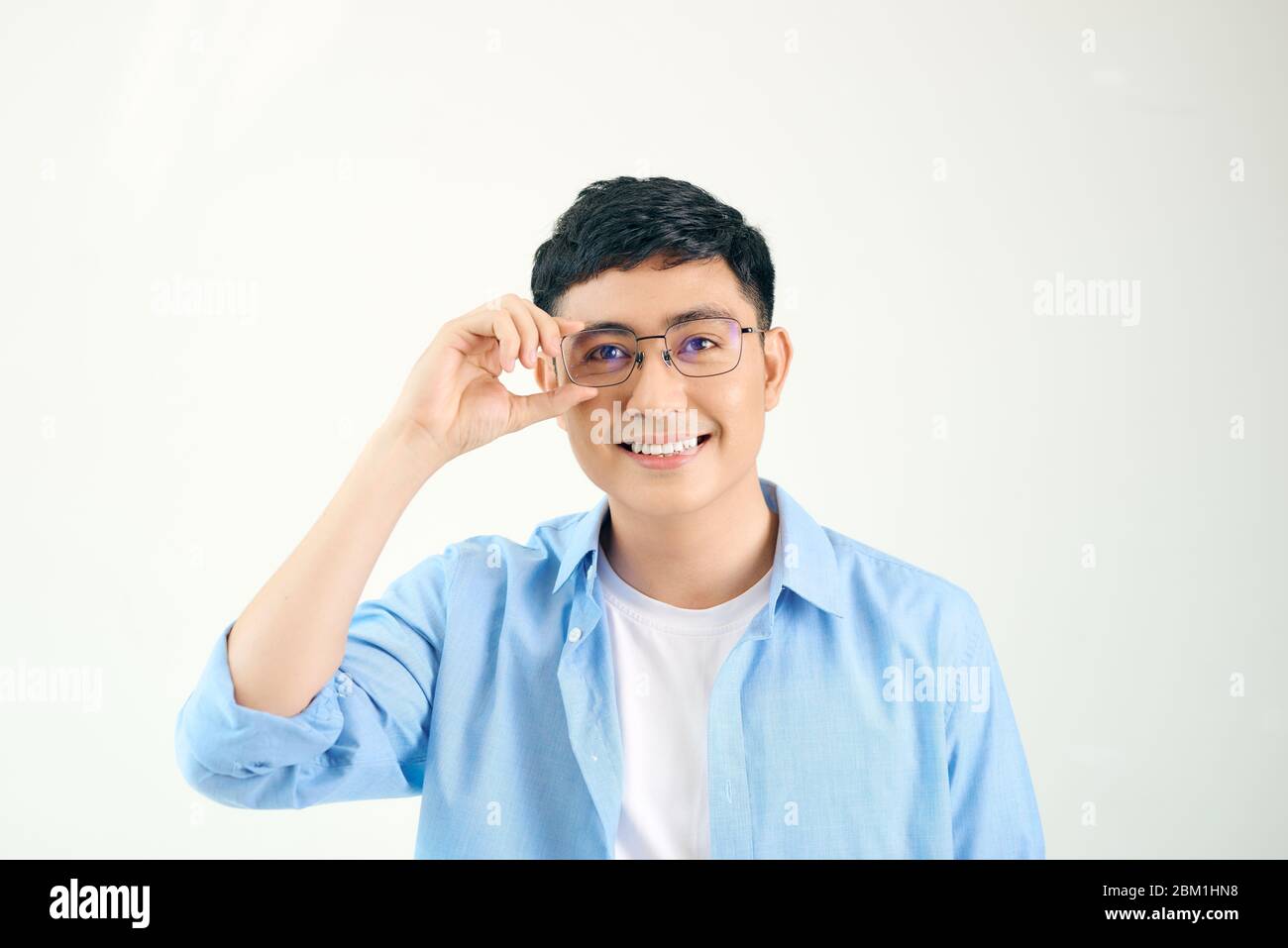 Closeup of friendly guy wearing eyeglasses. Young asian man adjusting glasses and staring at camera through lens. Vision and eye care concept Stock Photo