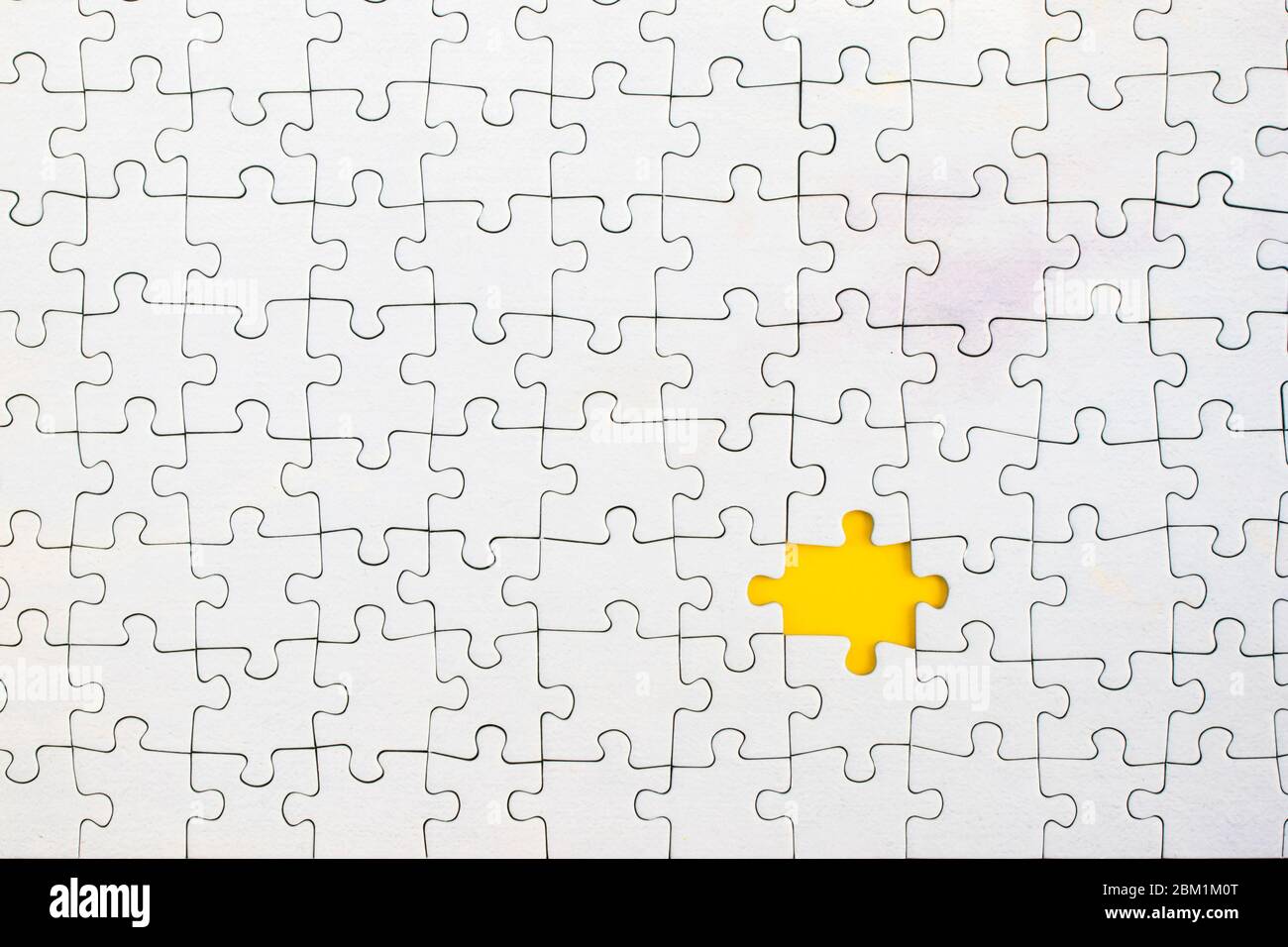 Yellow background showing through missing piece in white jigsaw puzzle