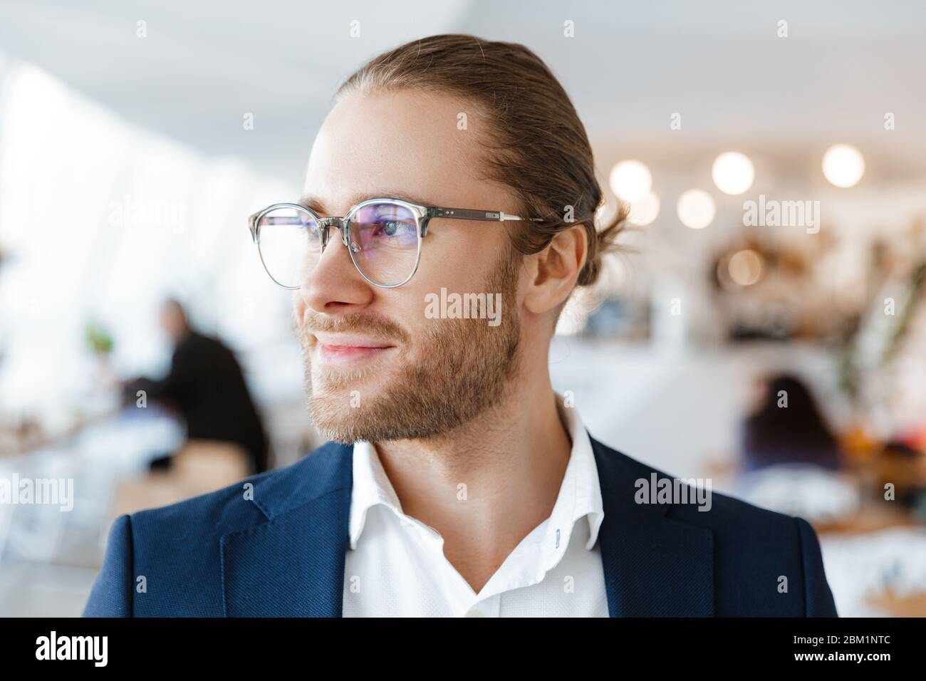 Image of handsome concentrated young businessman indoors in office looking aside. Stock Photo