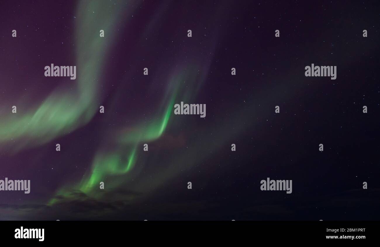 Zigzag green flashes in sky above black horizon northern lights. Stock Photo
