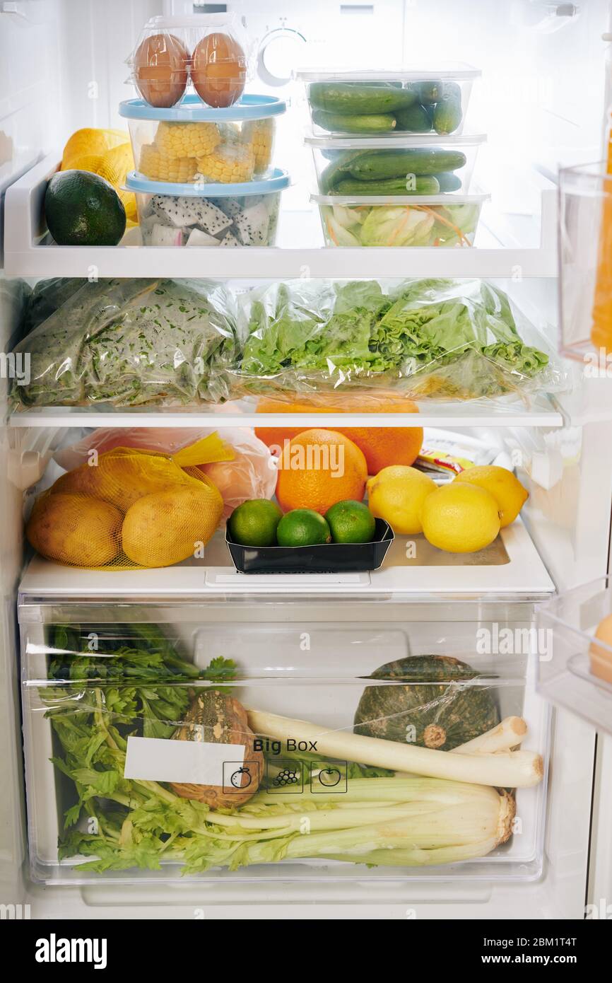 Opened fridge full of groceries like fruits, vegetables, greens and eggs, healthy eating concept Stock Photo