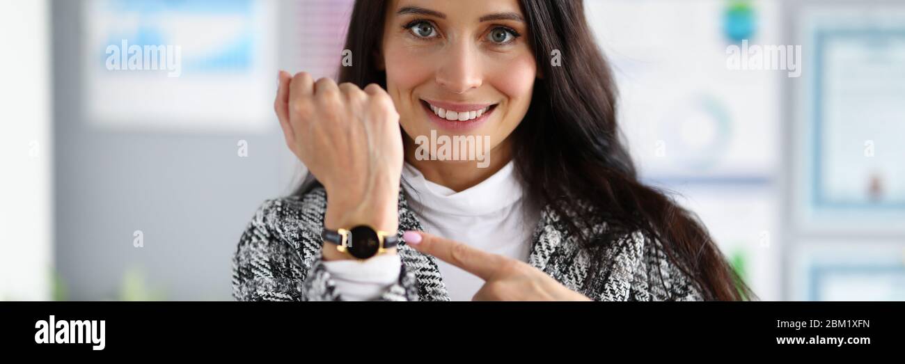 Smiling business woman pretty shows on watch Stock Photo