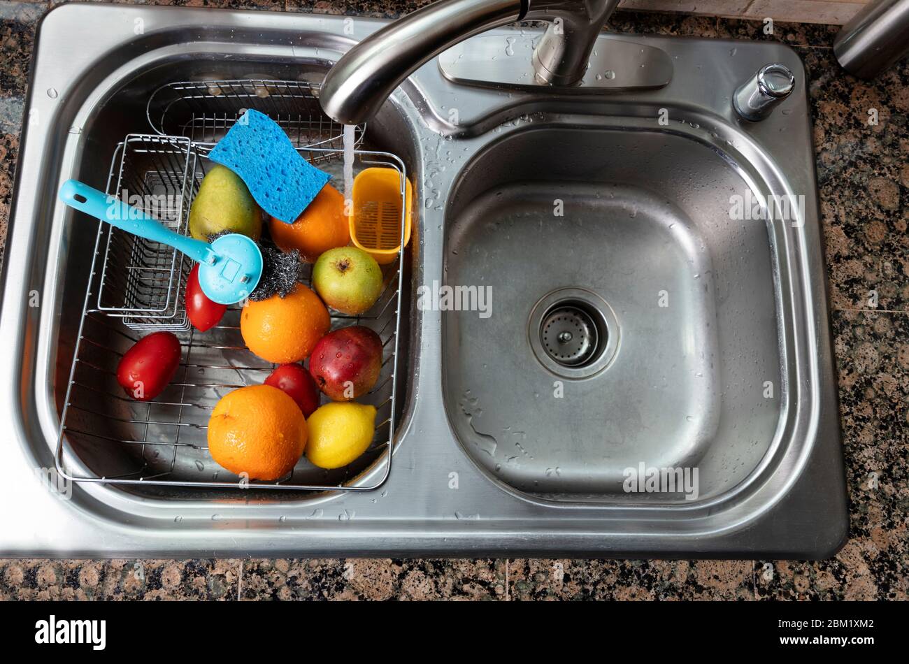 Fresh vegetables and fruits being washed in kitchen sink. Primary focus ...