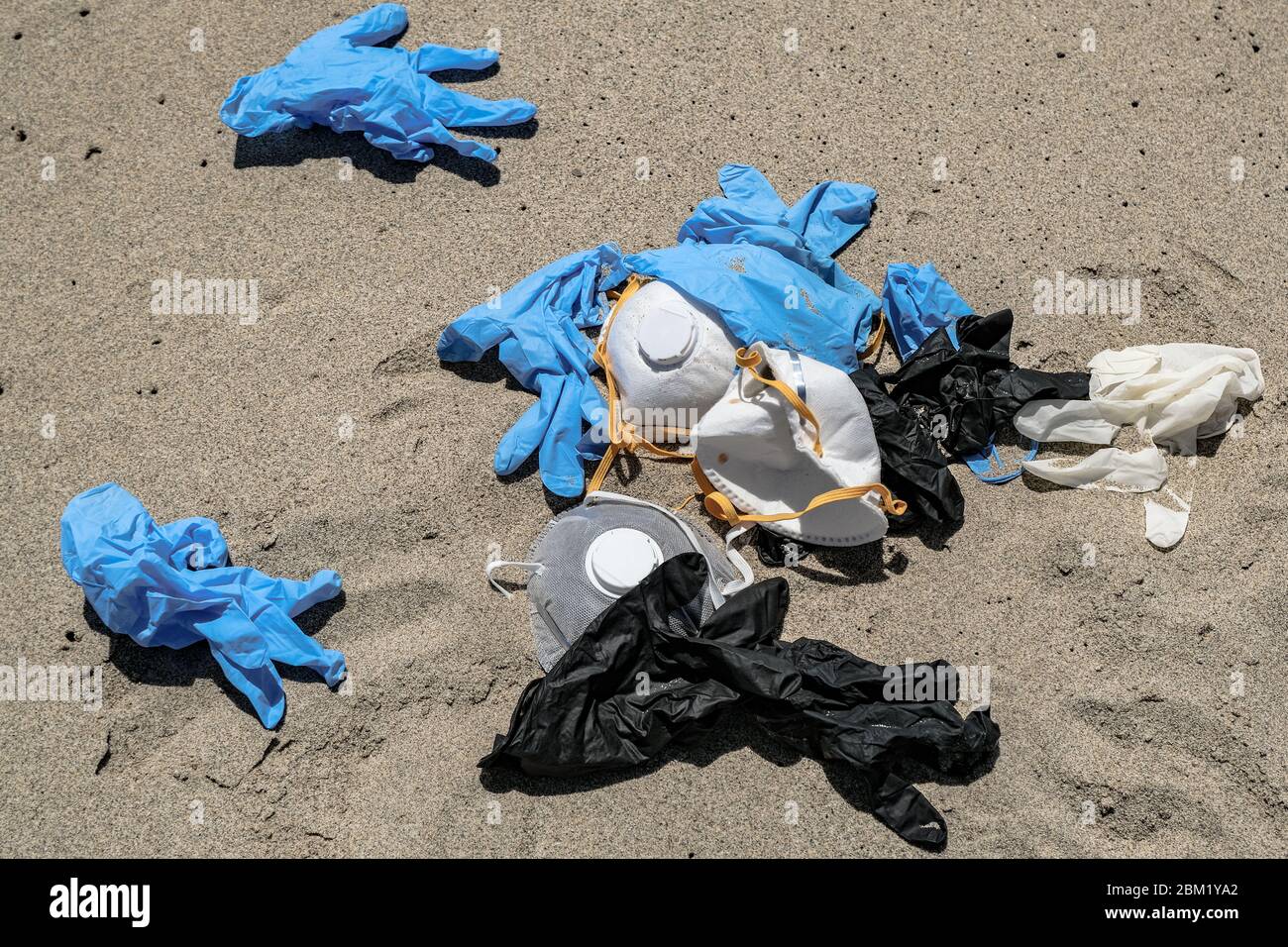 Protective virus mask and plastic gloves garbage trash on sandy sea coast,coronavirus covid pollution disease  Stock Photo