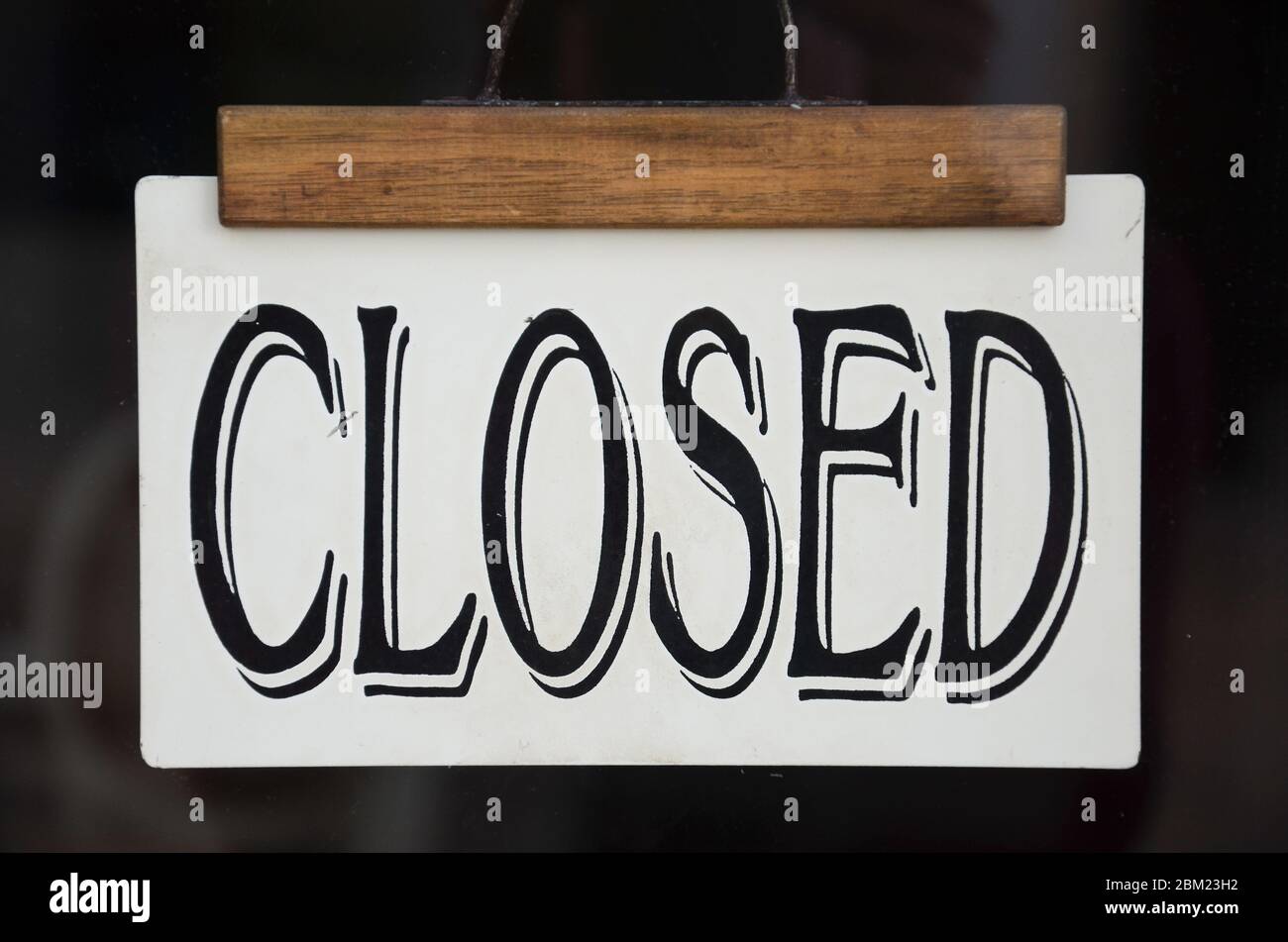 Sign Closed on the front window of a store. Black sign in Western-style font. Restaurants, bars and shops closed due to coronavirus, COVID-19 pandemic. Economical crisis, depression. Stock Photo