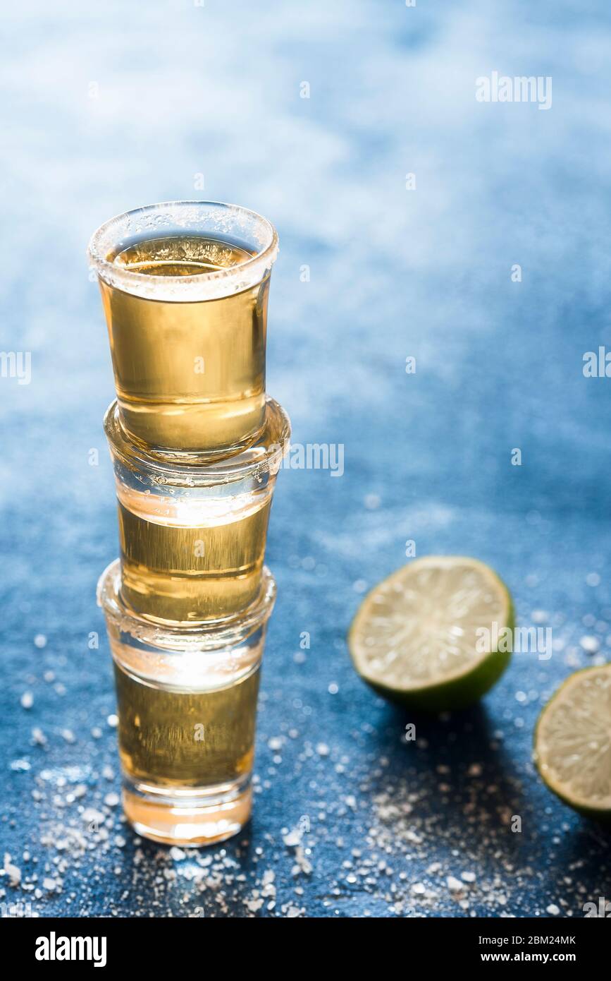 Three Shots Of Tequila Stacked On A Blue Table Gold Tequila Glass With Lime And Salt Aromatic Strong Mexican Alcohol Party Shots Stock Photo Alamy