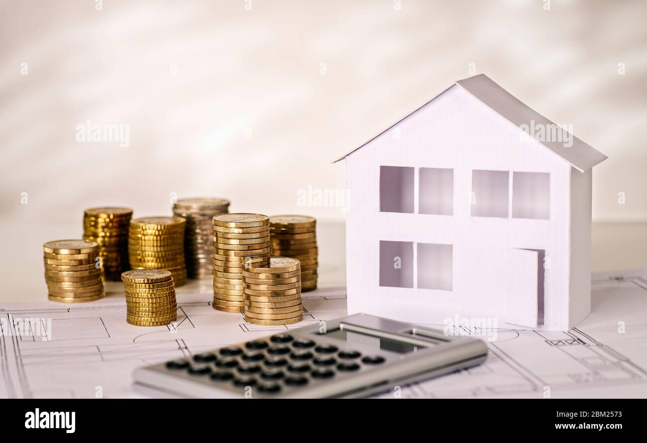 House with stacks of coins with calculator and building plan Stock Photo
