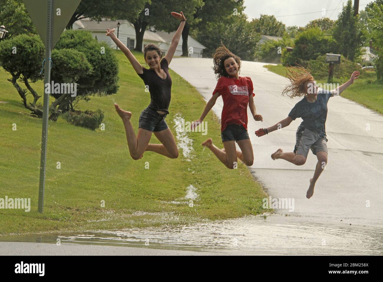 Young girls playing in a large puddle after heavy rain Stock Photo