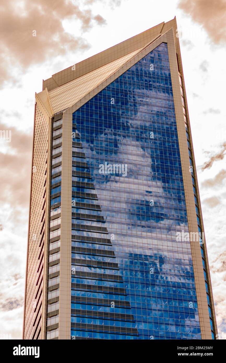 Charlotte, NC/USA - April 26, 2019:  Medium vertical shot of 'Duke Energy' building with blue window reflections against luminous sky. Stock Photo