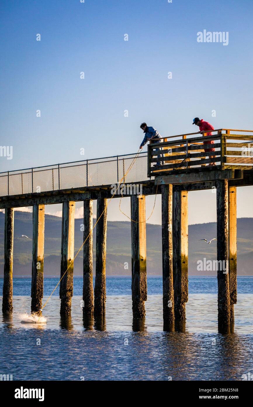 Crabbers toss their cage off the pier near Garibaldi, Oregon, USA. Stock Photo