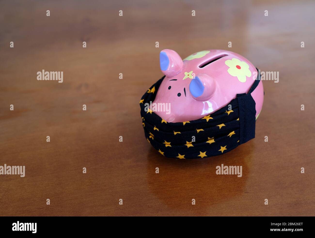 Lockdown and the financial impact: piggy bank wearing a face mask Stock Photo