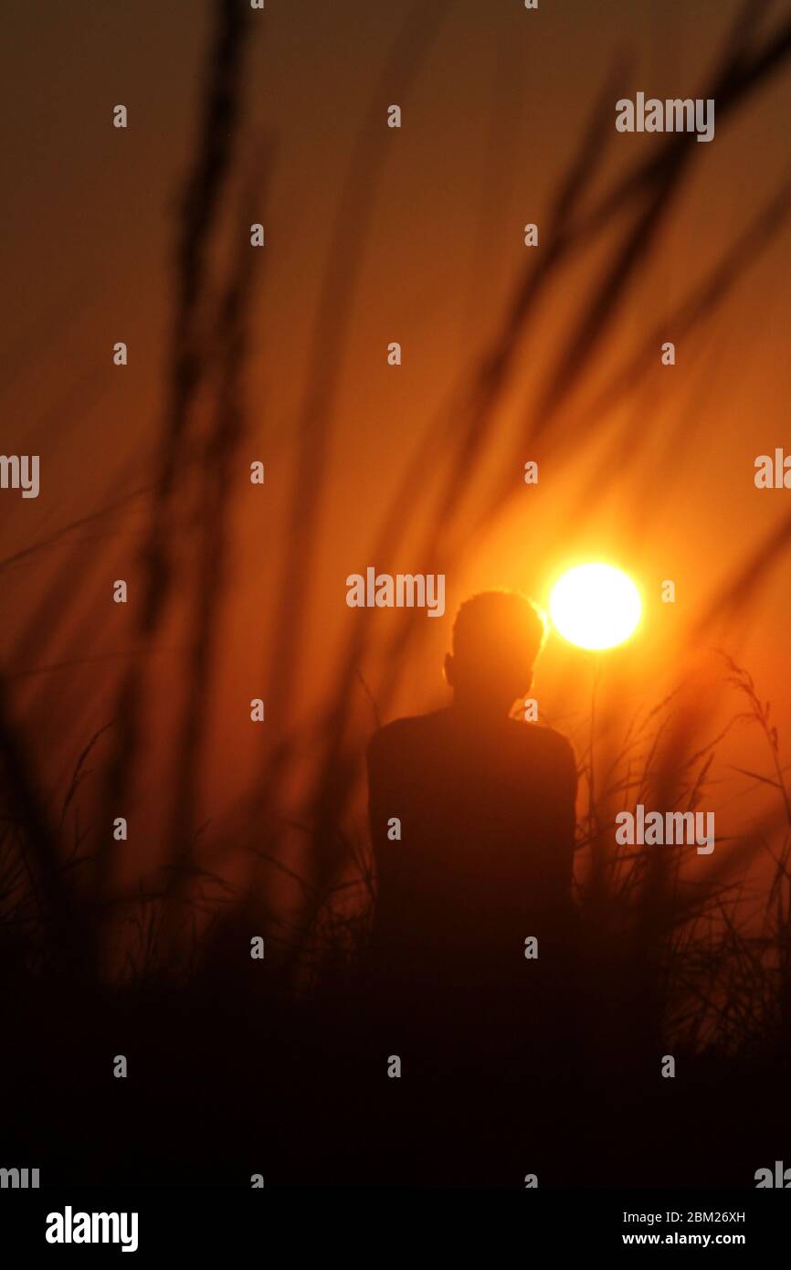 Silhouette of young man watching the sunset from the sea shore Stock ...