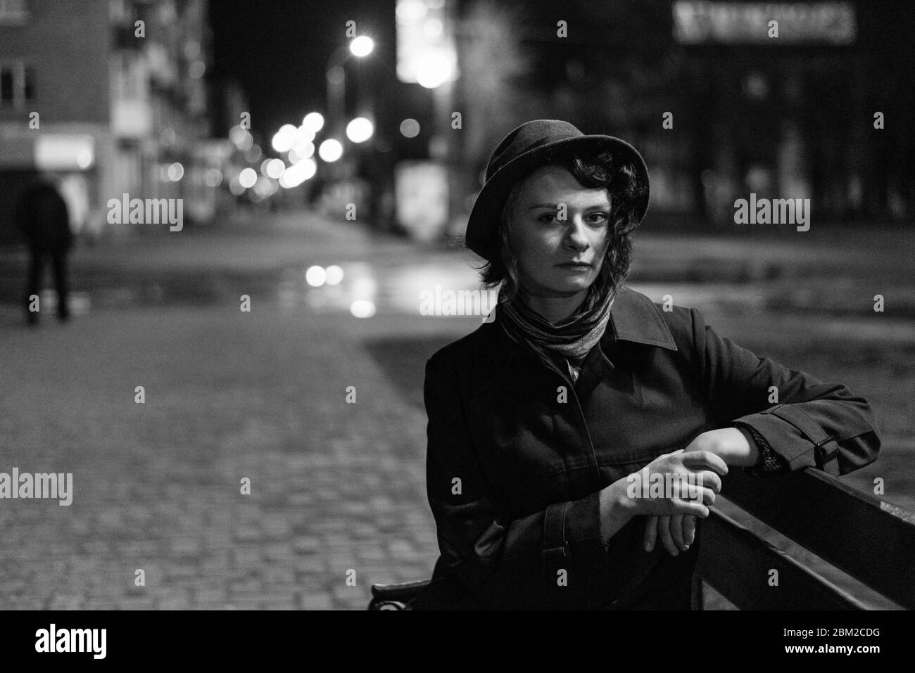 Cute girl in a hat sits on a bench on the street at night, photographed ...