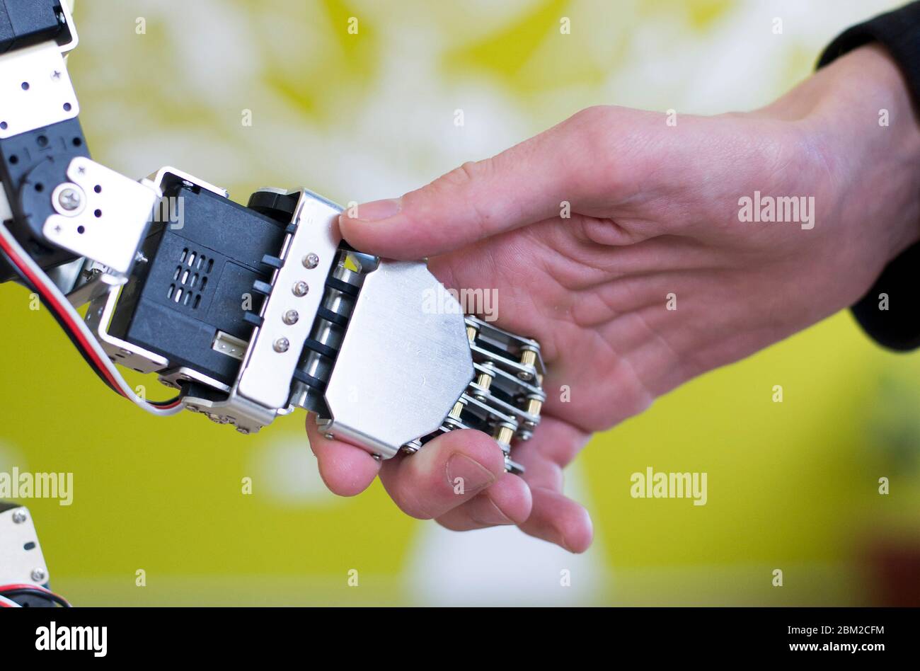 Photo of a human hand holding a robot hand with a handshake Stock Photo ...