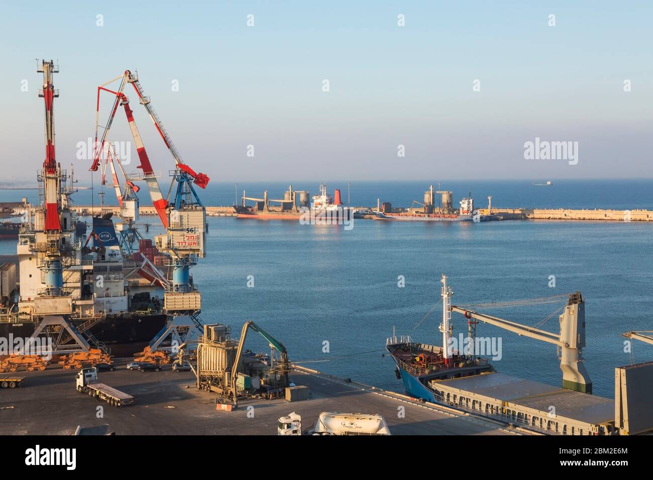 Four-link cargo loading cranes on dock and docked cargo ships in Ashdod Port, Israel Stock Photo