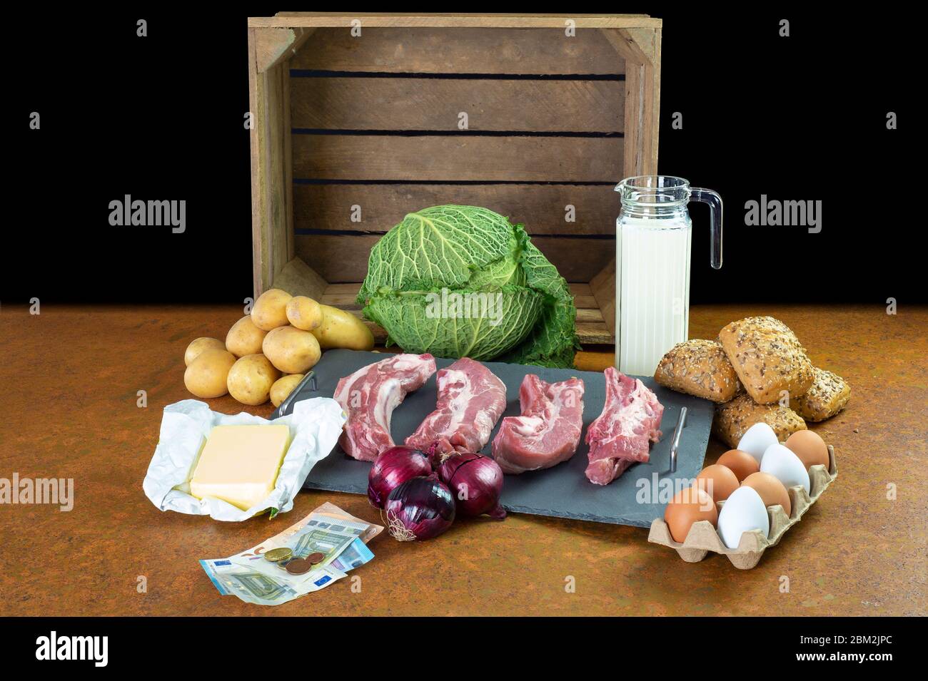Food for basic needs. In the background is a wooden fruit box. In the foreground are euro banknotes. Stock Photo