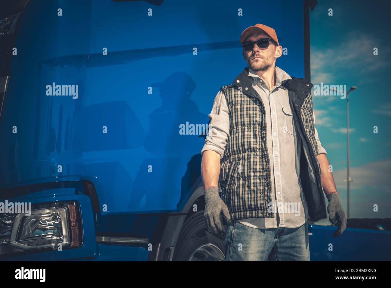 Close Up Of Caucasian Male Truck Operator Standing In Front Of Large Blue Cabin Of Vehicle. Stock Photo