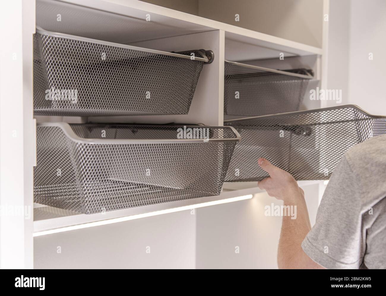 Caucasian Handyman Assembles And Adjusts Silver Metal Baskets In Walk