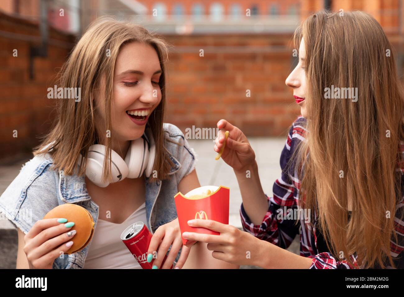 Young woman eating mcdonalds hamburger snack lunch hires stock