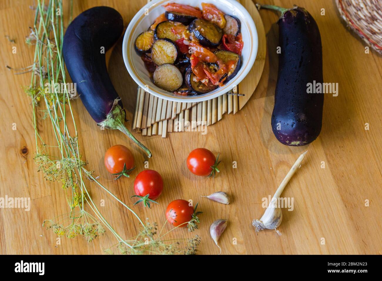 Homemade vegetable stew lecho with tomatoes and eggplants flatlay background on wooden table Stock Photo