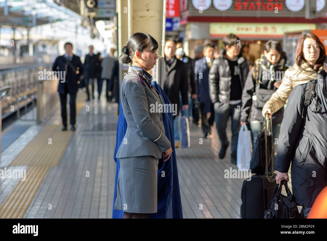 Osaka / Japan - December 20, 2017: Female train attendant standing at Shin-Osaka Railway Station, while passengers are waiting in line to board the sh Stock Photo