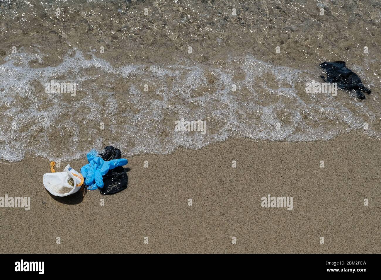 Protective virus masks and plastic gloves garbage trash on sandy sea shore,coronavirus covid pollution disease  Stock Photo