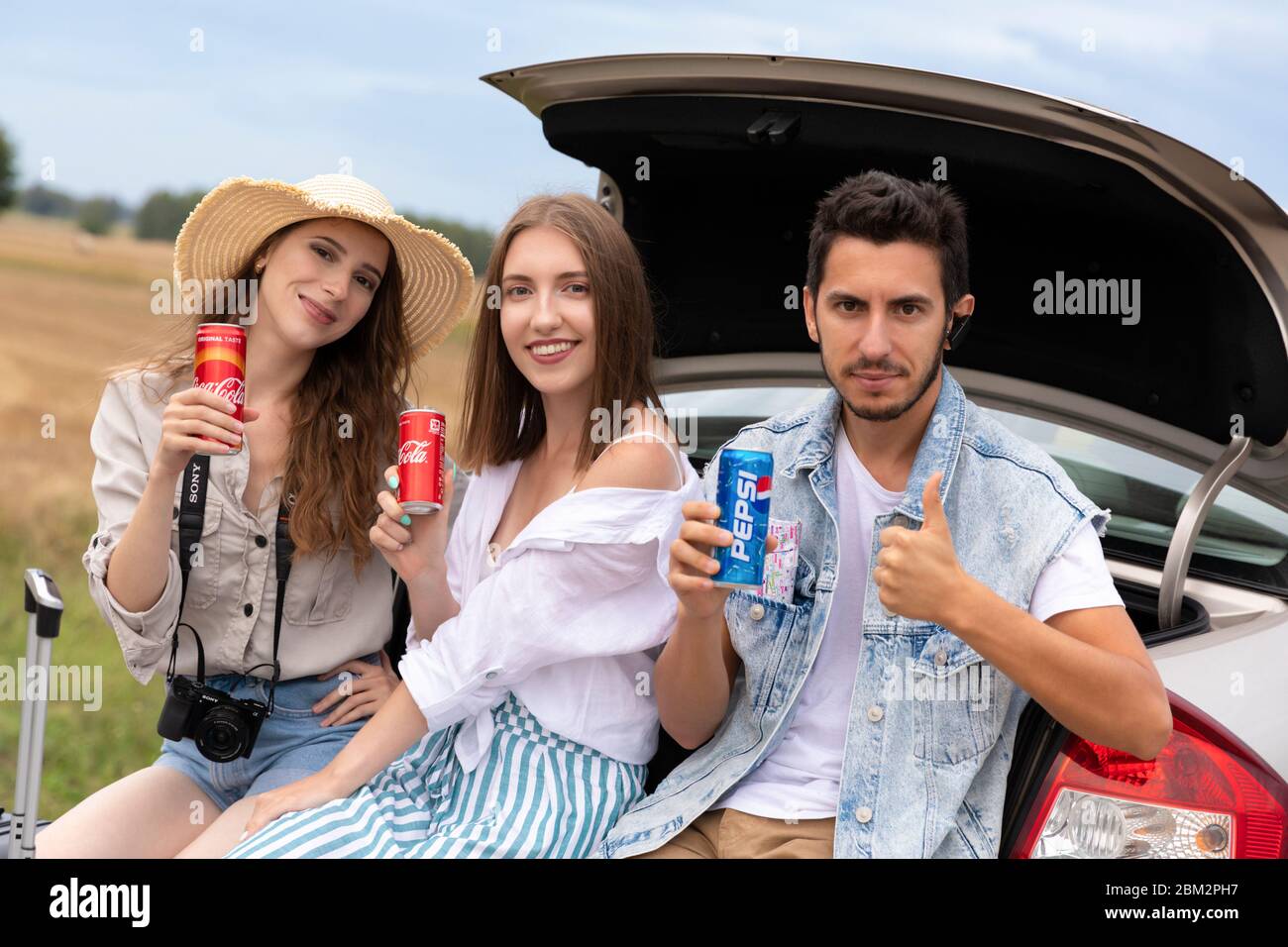LODZ, POLAND - August 12, 2019: man chose a Pepsi drink for himself, while two girls drink Coca-Cola products. Their opinions were divided. Stock Photo
