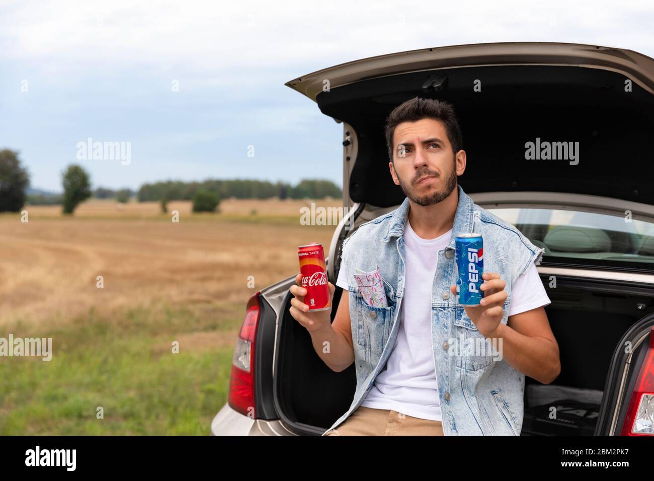 LODZ, POLAND - August 12, 2019: man is trying to choose a drink for himself. His choice is between Coca-Cola and Pepsi products. Stock Photo
