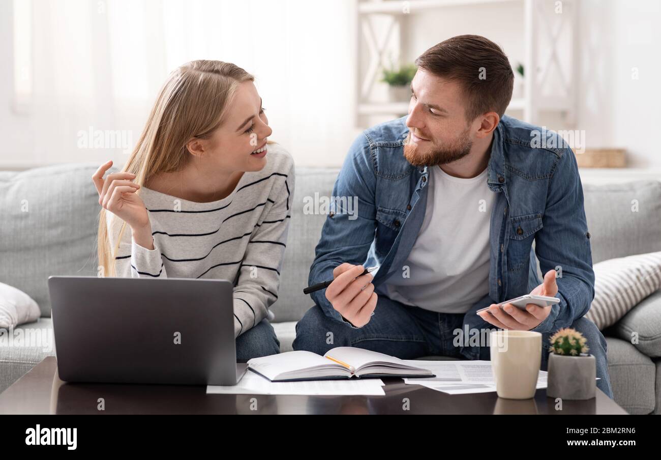 Positive young couple calculating finances at home Stock Photo