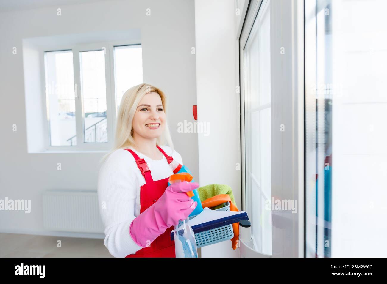 Cleaning lady with a bucket and cleaning products on office background ...