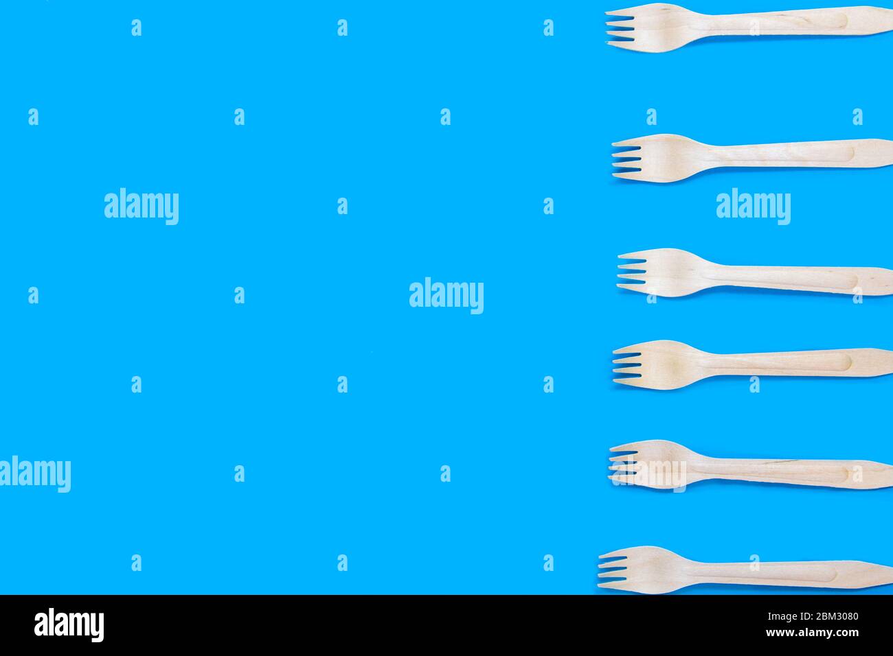 Eco friendly disposable wooden forks on blue background.ecology Stock