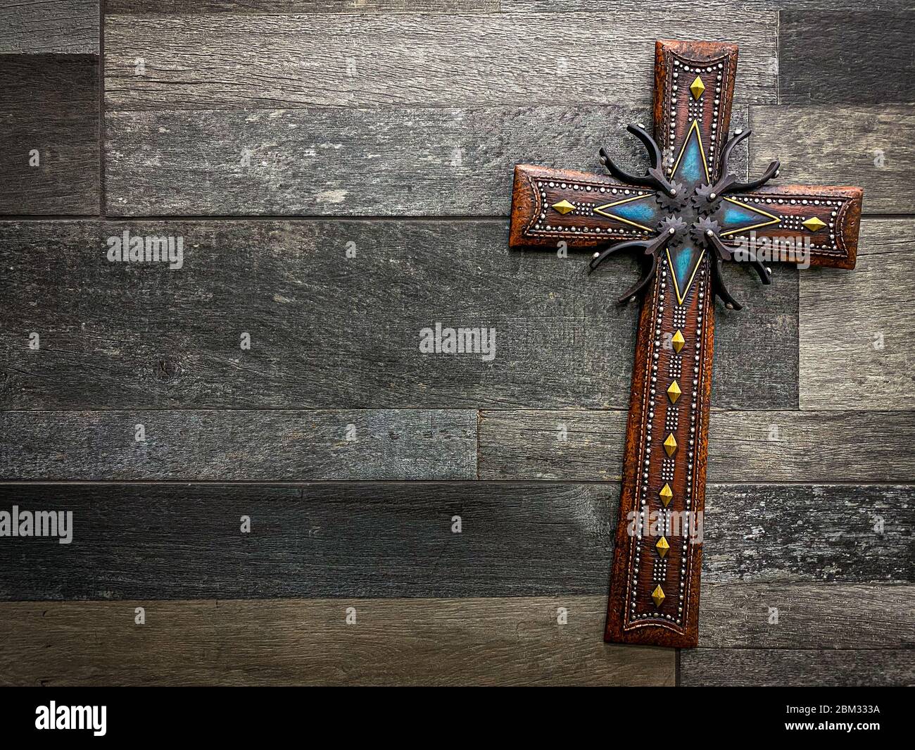 Beautiful decorative christian cross with Texan inspired motifs with spurs and cowboy belts. Concept of religion and beliefs in the USA Stock Photo