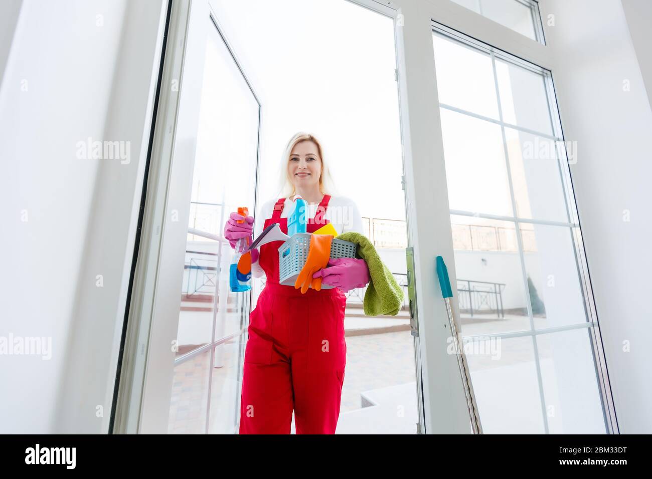 Cleaning lady with a bucket and cleaning products on office background ...