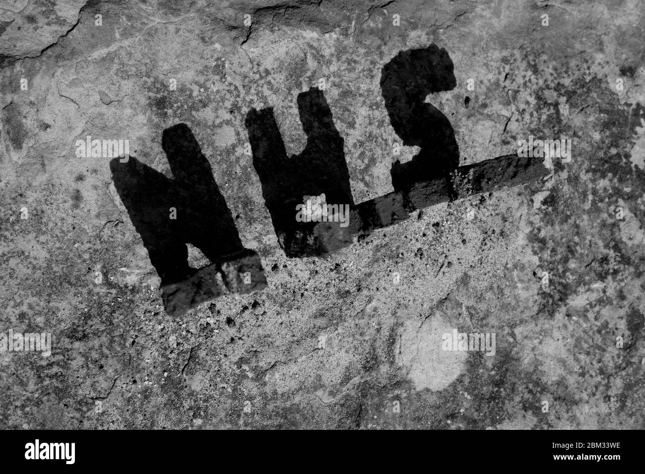 A Shadow of the Letters 'NHS', Showing the Sun Cast of the Shapes on a Rock Base with a Gritted Texture to the Stone Surface. Stock Photo