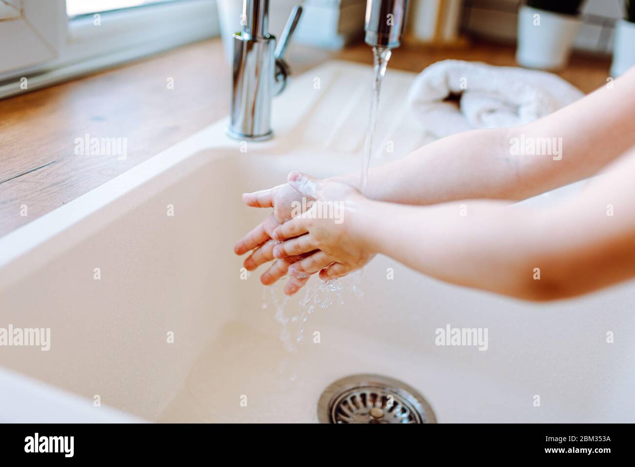 Little girl washing hands in the lingh kitchen before eating. Hygiene and healthcare concept. Face is not visible Stock Photo