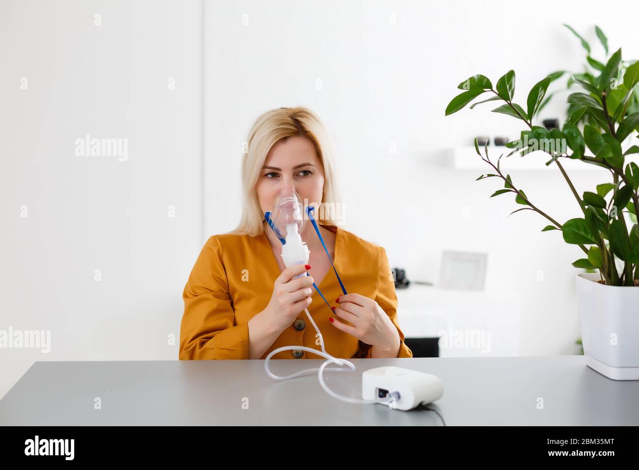 woman makes inhalation nebulizer at home. holding a mask nebulizer