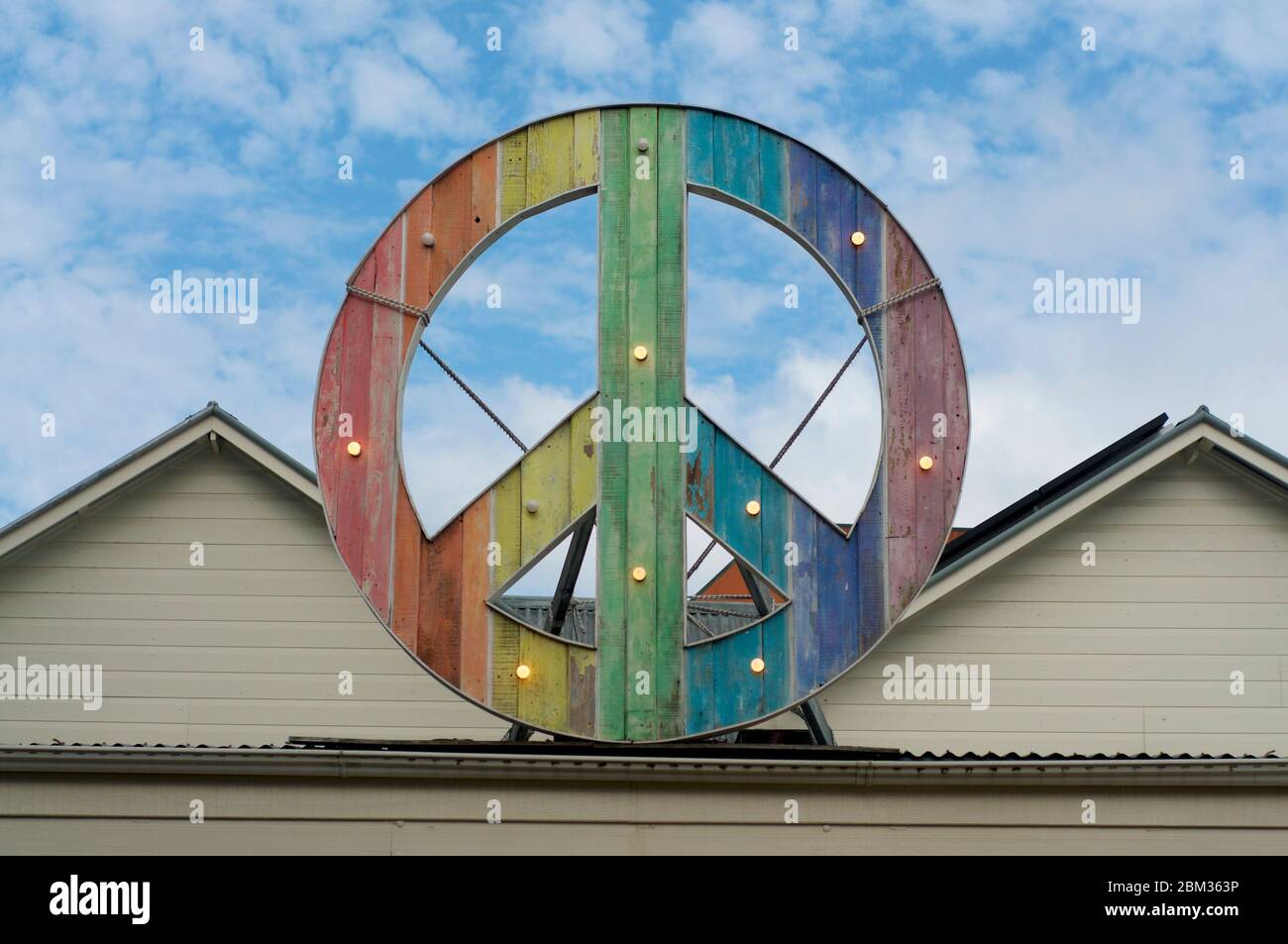 Rainbow colored peace sign hanging on top of a building in Byron Bay Stock Photo