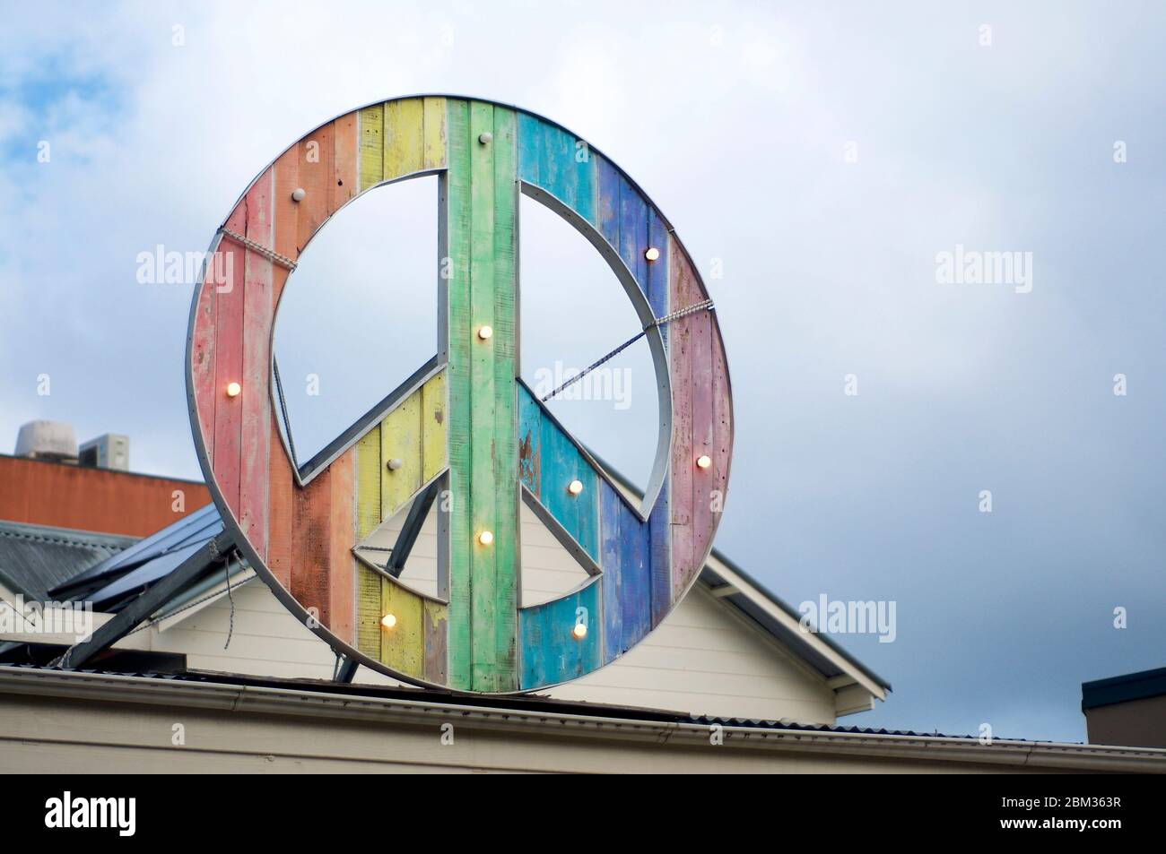 Rainbow colored peace sign hanging on top of a building in Byron Bay Stock Photo