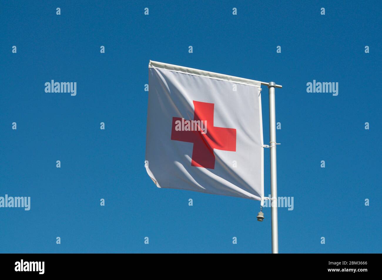 The flag of International Red Cross and Red Crescent Movement against a blue sky in Manno, Switzerland. The Red Cross is an international humanitarian Stock Photo