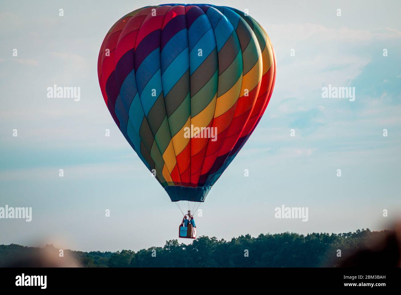 Rainbow hot air balloon flying through the sky at sunset Stock Photo ...