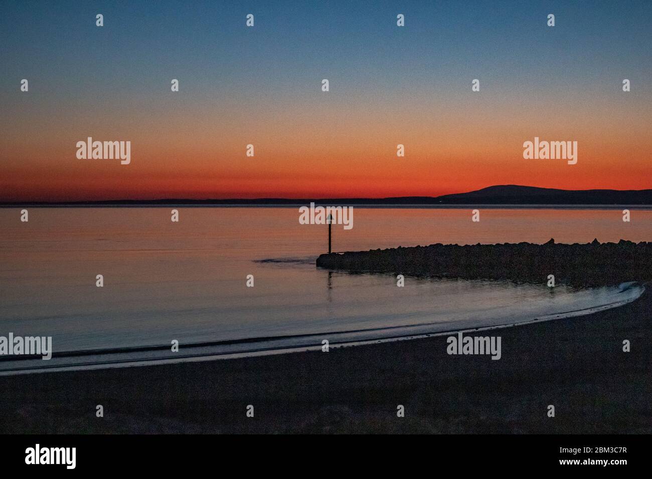 Morecambe, Lancashire, United Kingdom. 6th May, 2020. Dusk afterglow acros Morecambe Bay from the Grosvenor Breakwater towards Black Coombe. Credit: Photographing_North/Alamy Live News Stock Photo