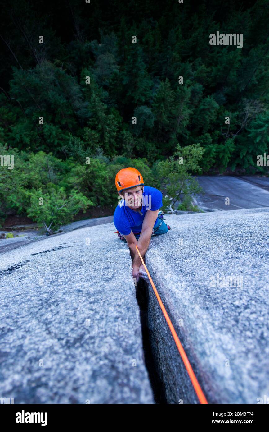 Man smiling and looking up at camera while climbing off width Squamish Stock Photo