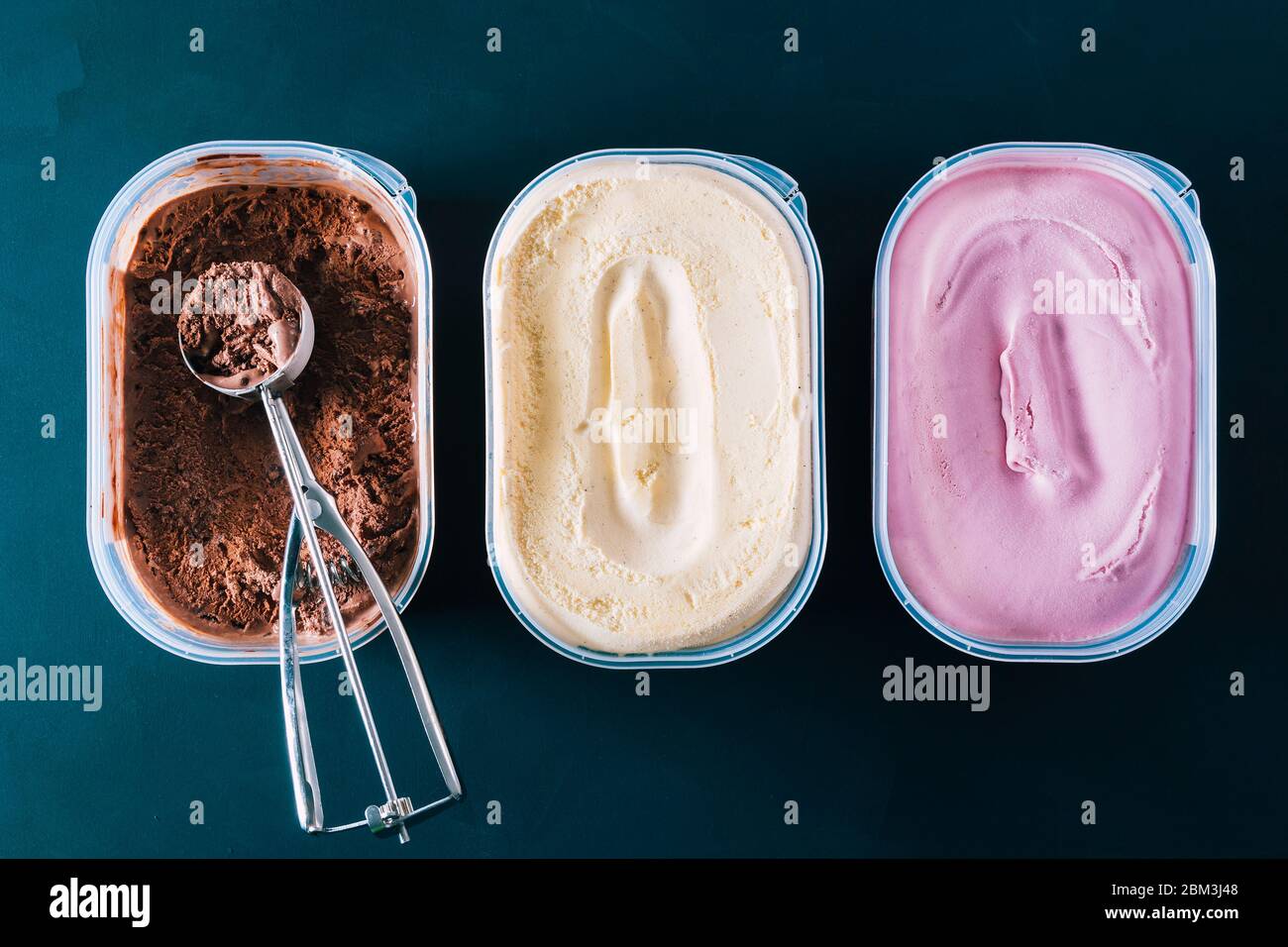 Chocolate, vanilla and strawberry ice cream tubs. To prepare Neapolitan ice cream ready to eat on a hot summer day or as a delicious dessert. Stock Photo