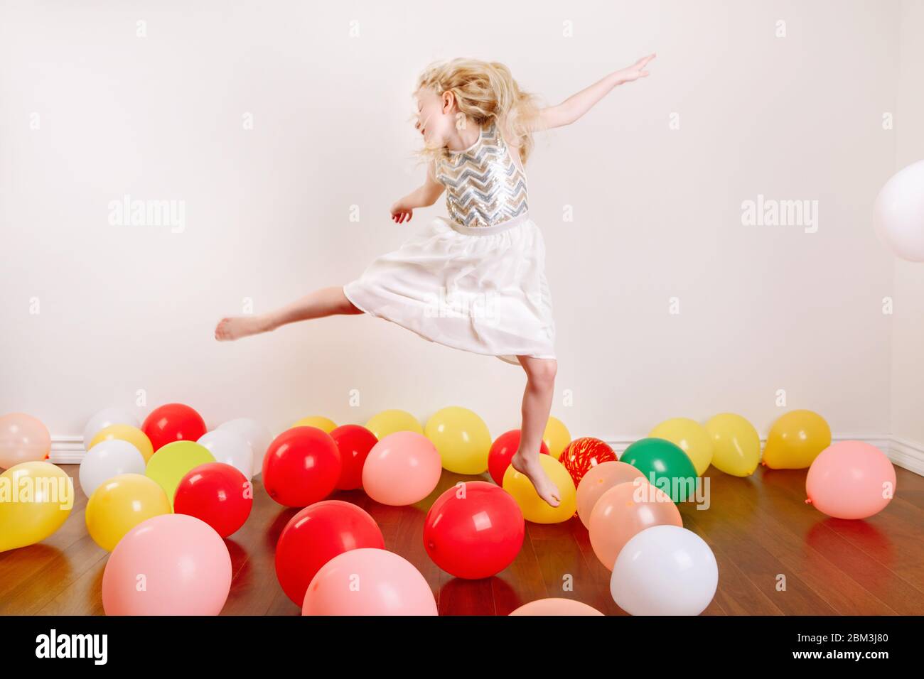 Cute adorable little girl celebrating birthday at home. Lovely girl child with colorful balloons having fun. Quarantine birthday party at home alone d Stock Photo