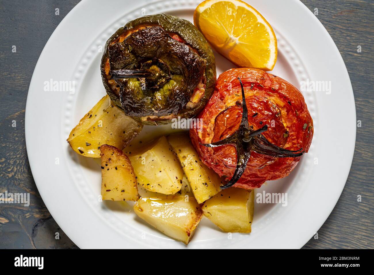 Vegan stuffed tomatoes and green pepper and roasted potatoes. Stock Photo