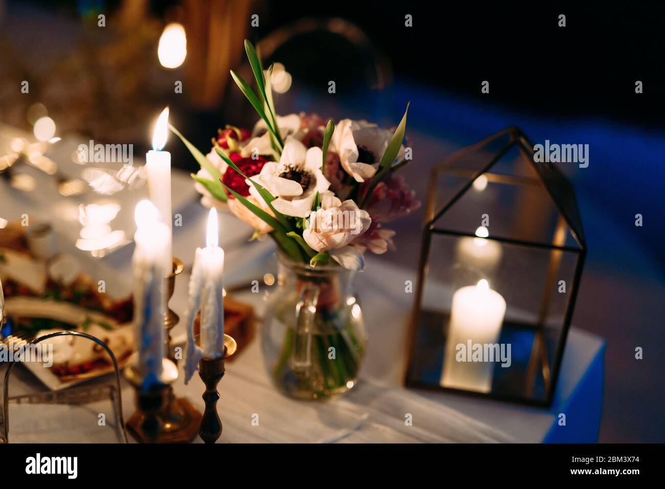 Wedding dinner table reception. Wedding table decoration - white branch  from a tree, crystal pendants, candles in glass spheres, on a white table  with Stock Photo - Alamy