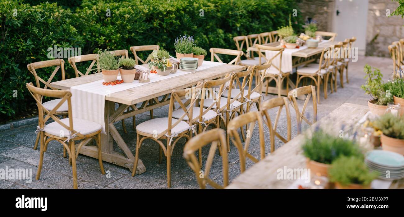 Wedding dinner table reception at sunset outside. Ancient rectangular  wooden tables with rag runner, wooden vintage chairs, lavender pots, cherry  Stock Photo - Alamy
