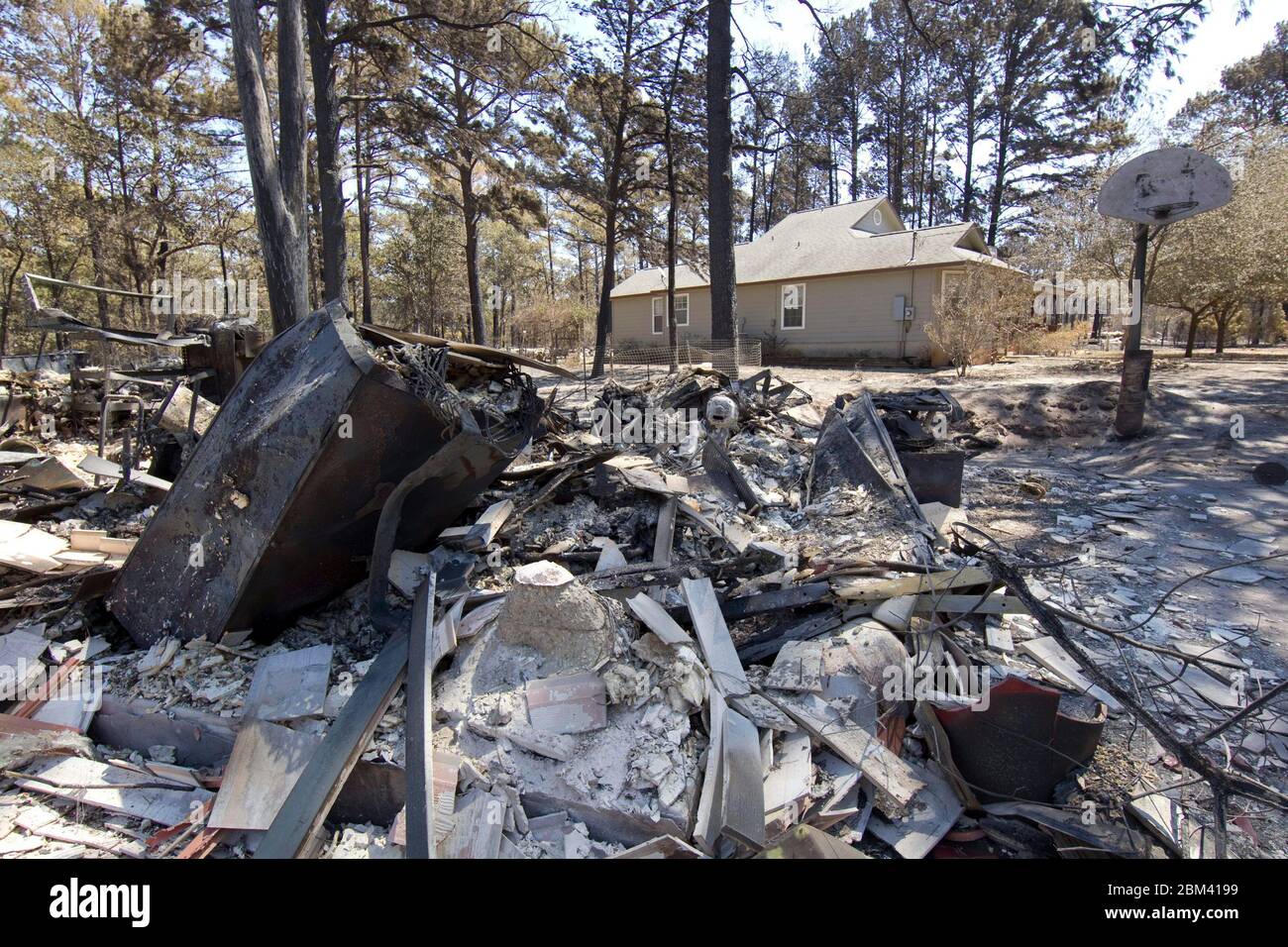 Bastrop County Texas USA, September 9, 2011: A home sits untouched while the garage next to it lies in ruins off Hwy 21  after wildfire raced through the piney woods in Bastrop County 30 miles east of Austin. The fires destroyed 1,400 houses and scorched over 38,000 acres while it raged out of control for five days.  ©Bob Daemmrich Stock Photo